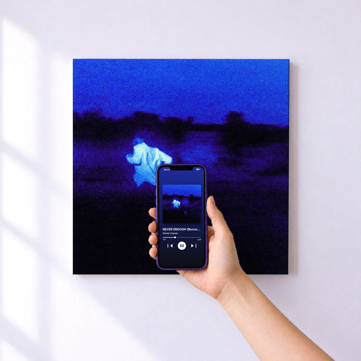 Affiche connectée NEVER ENOUGH (Bonus Version) de Daniel Caesar au mur : l'album se lance en approchant le téléphone