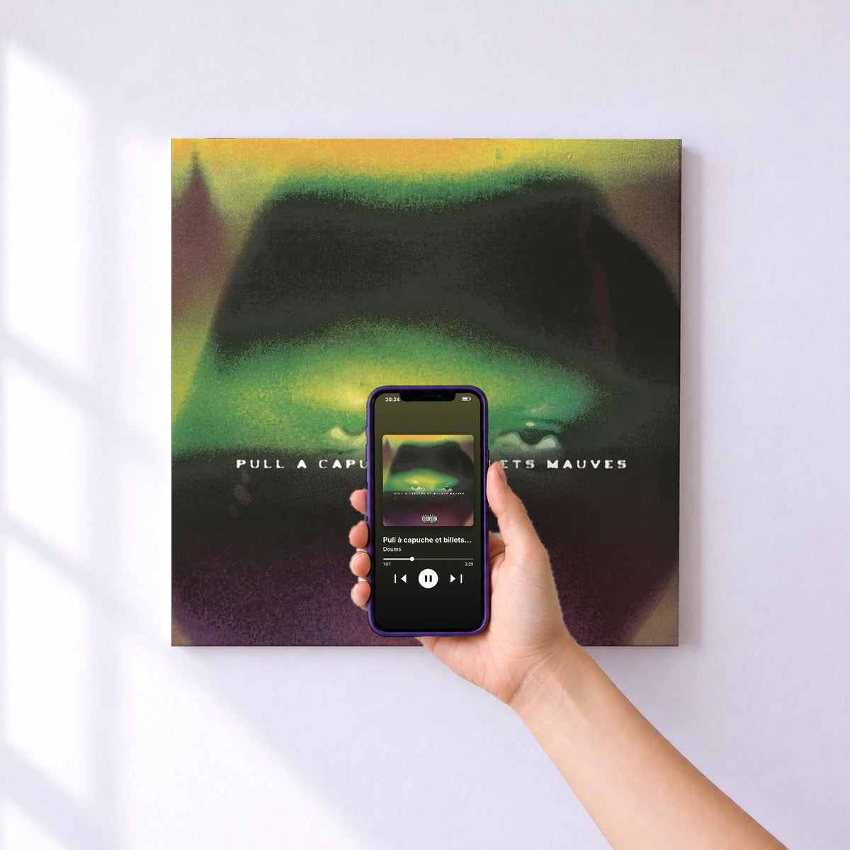 Affiche connectée Pull à capuche et billets mauves de Doums au mur : l'album se lance en approchant le téléphone