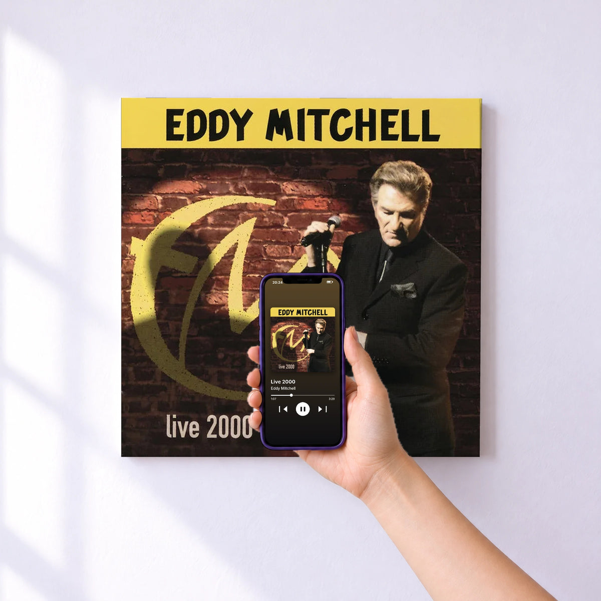 Affiche connectée Live 2000 de Eddy Mitchell au mur : l'album se lance en approchant le téléphone