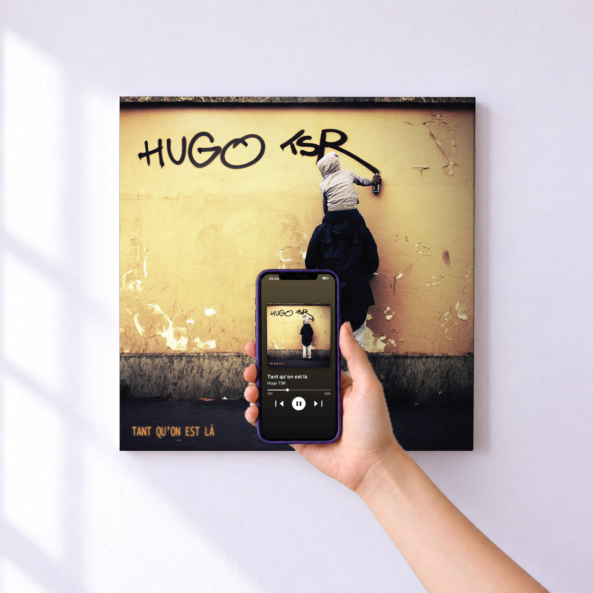 Affiche connectée Tant qu'on est là de Hugo TSR au mur : l'album se lance en approchant le téléphone